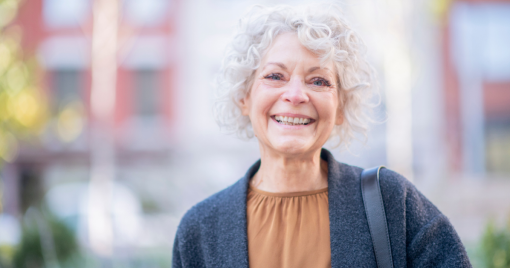 A woman is happy despite dealing with senior incontinence due to managing it as best she can.