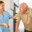 Caregiver smiling at senior man using a walker